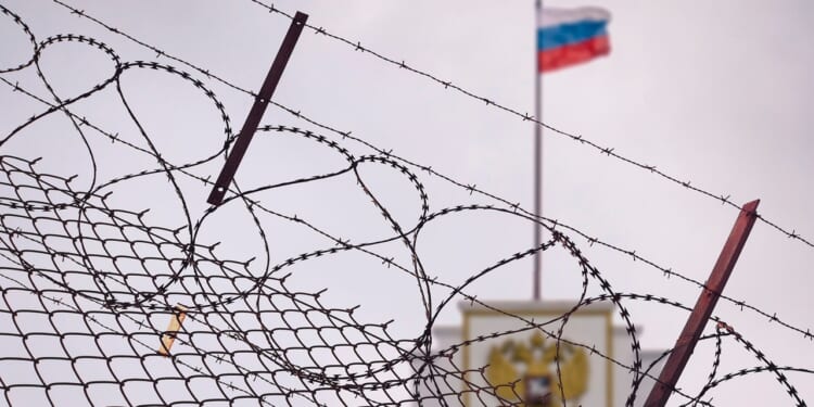 A Russian flag behind barbed wire.