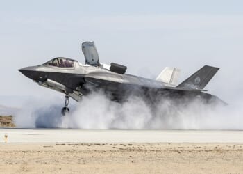 An F-35B landing in a cloud of dust.