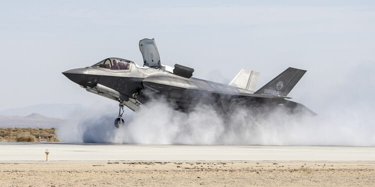 An F-35B landing in a cloud of dust.