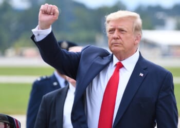 Trump raising his fist while giving a speech.