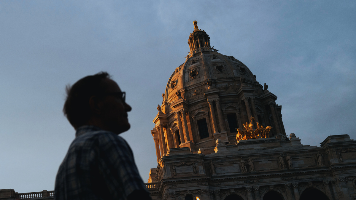 A man walks in front of the Minnesota State Capitol building at sunset in St. Paul, Minnesota.
