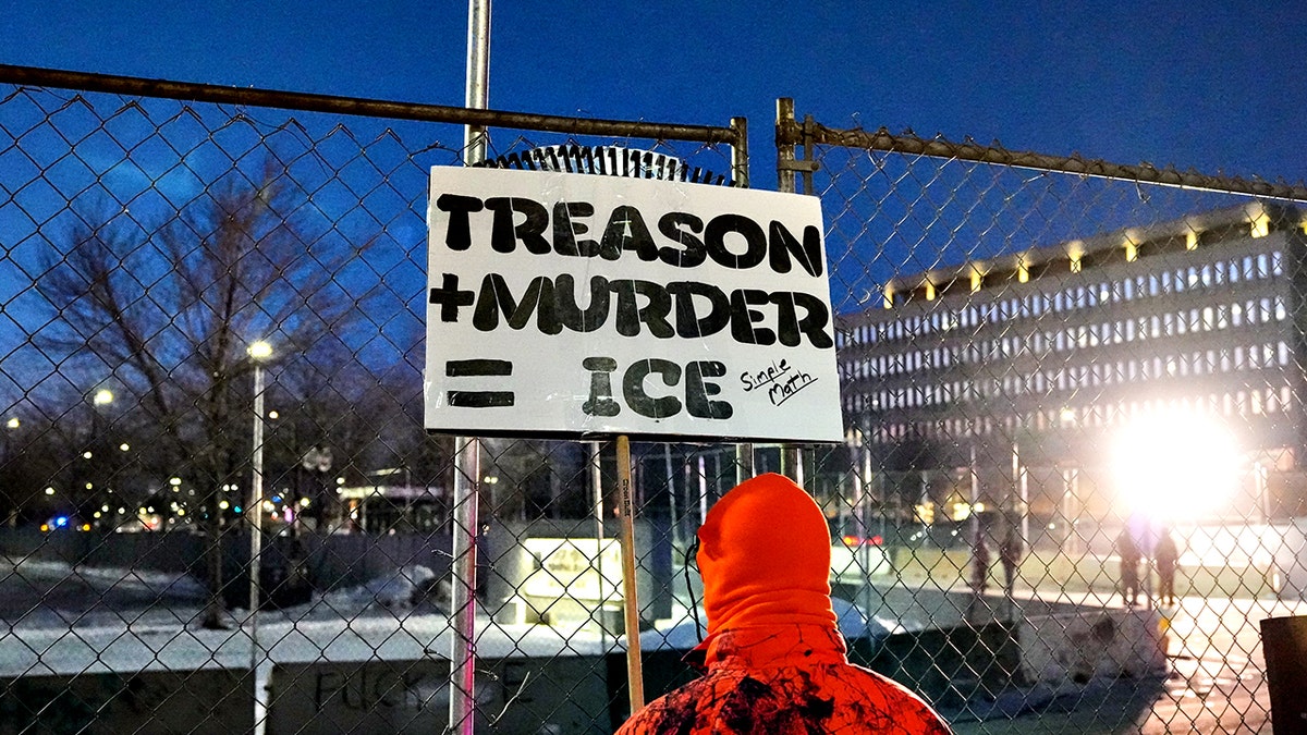 protester holds a sign outside the Bishop Henry Whipple Federal Building