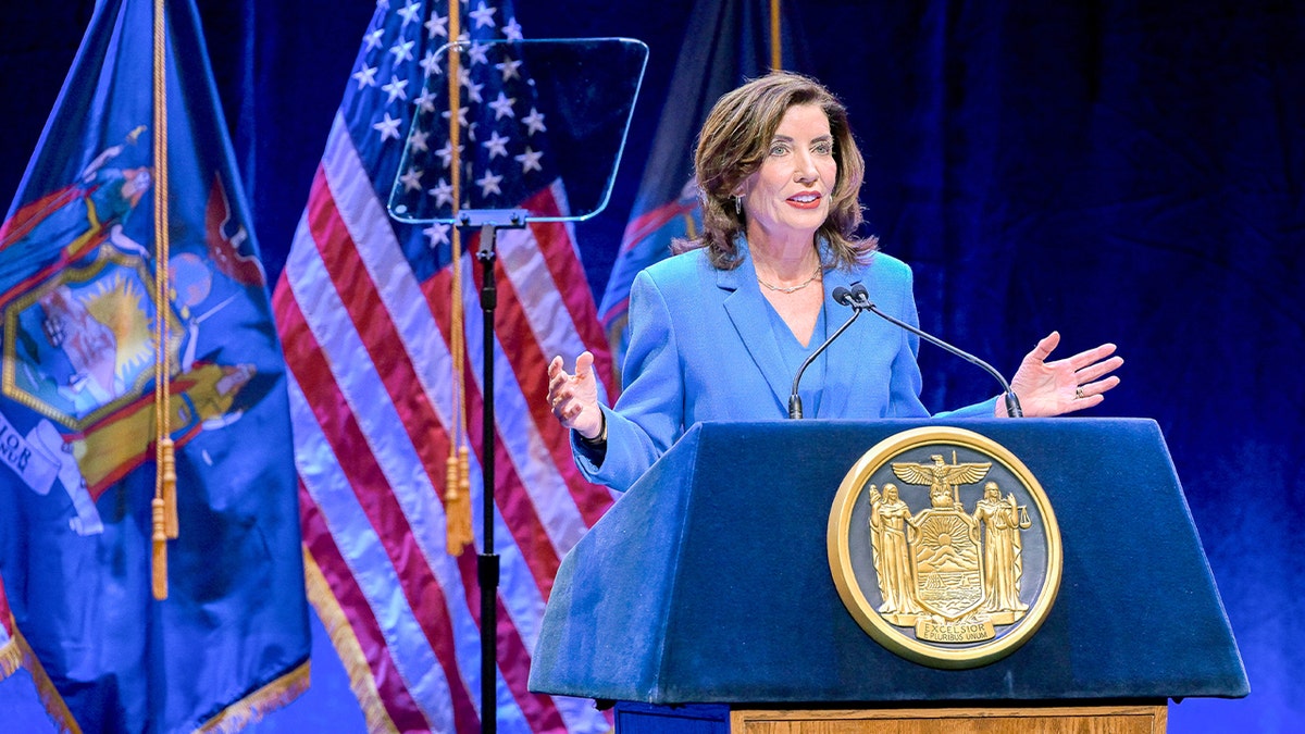 Kathy Hochul stands on a stage addressing an audience inside a theater.