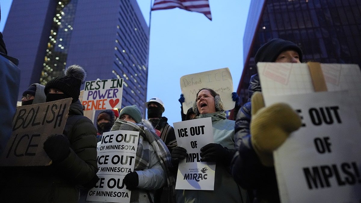 Demonstrators holding signs and standing outside a brick building.