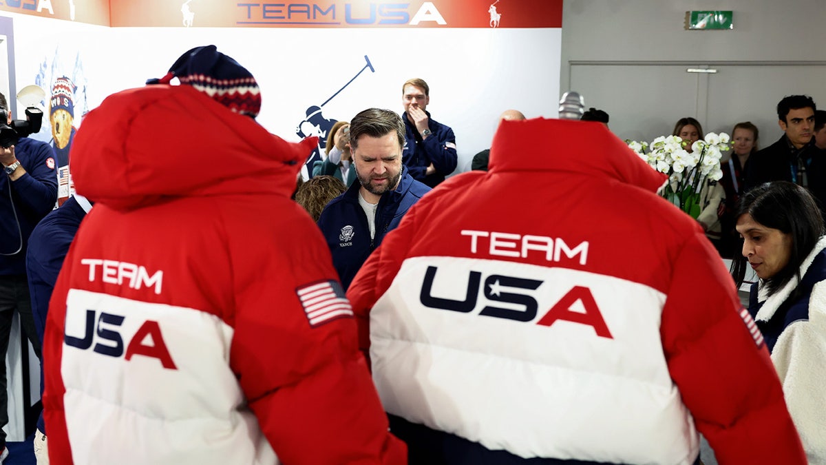 Vance speaks with two people in "Team USA" coats