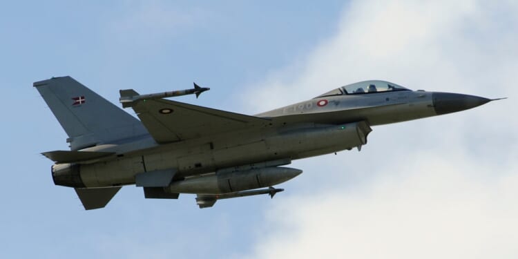 A Danish F-16 in flight against a cloudy sky.