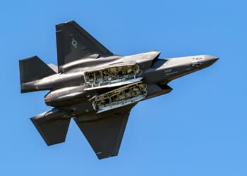 An F-35 in flight, from the underside, with open weapons bays.