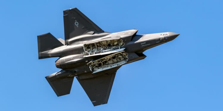 An F-35 in flight, from the underside, with open weapons bays.