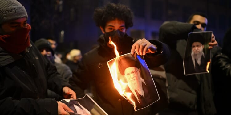 Several protesters burning pictures of Ayatollah Ali Khamenei.