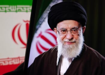 A picture of Ayatollah Ali Khamenei against an Iranian flag.