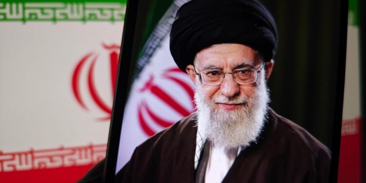 A picture of Ayatollah Ali Khamenei against an Iranian flag.