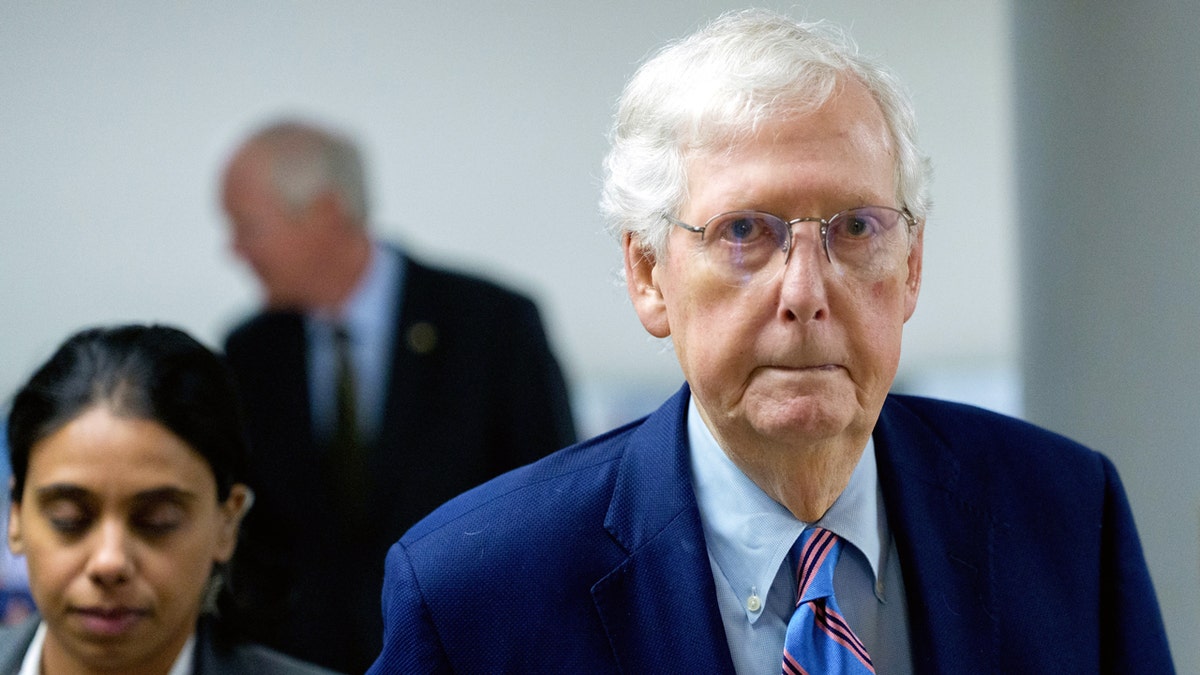 Mitch McConnell walking in front of his assistants.