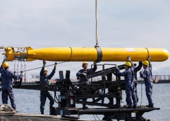 A group of Japanese sailors loading a torpedo onto a submarine.