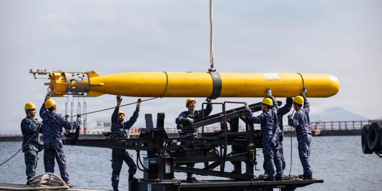 A group of Japanese sailors loading a torpedo onto a submarine.