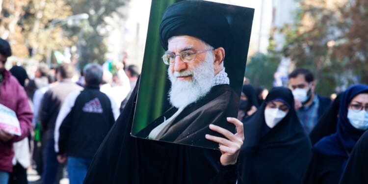 Woman holding a portrait of Iranian Supreme Leader Ali Khamenei.