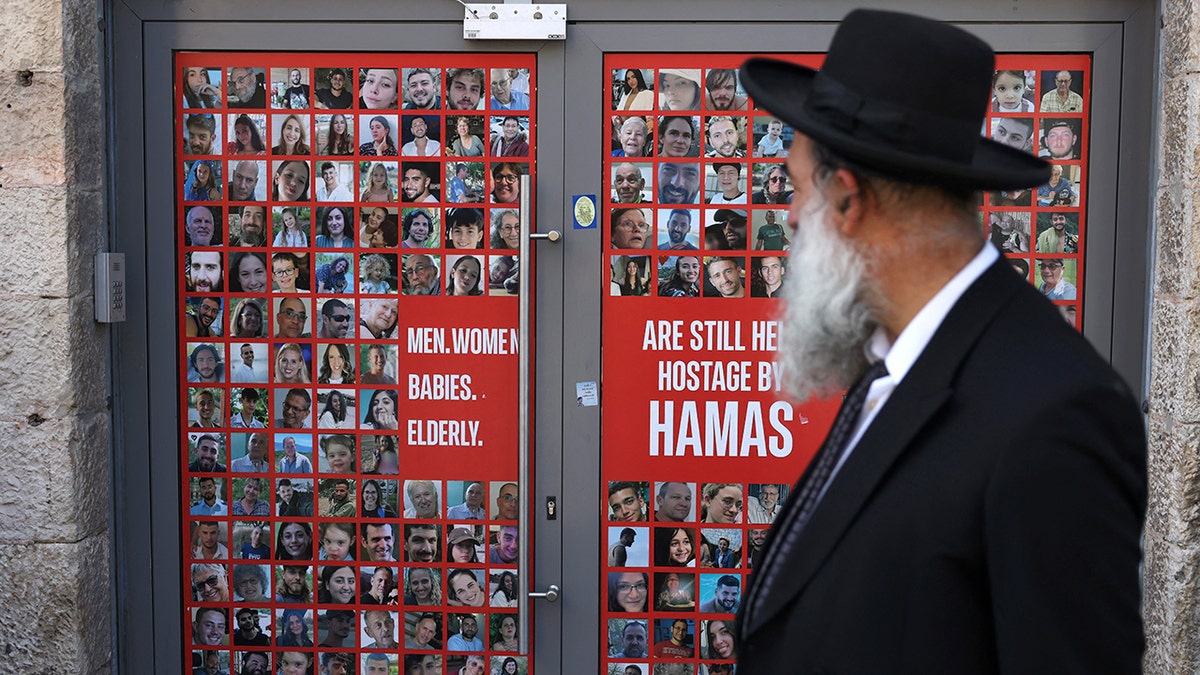 An Israeli walks past banner with the portraits of Israelis held hostage