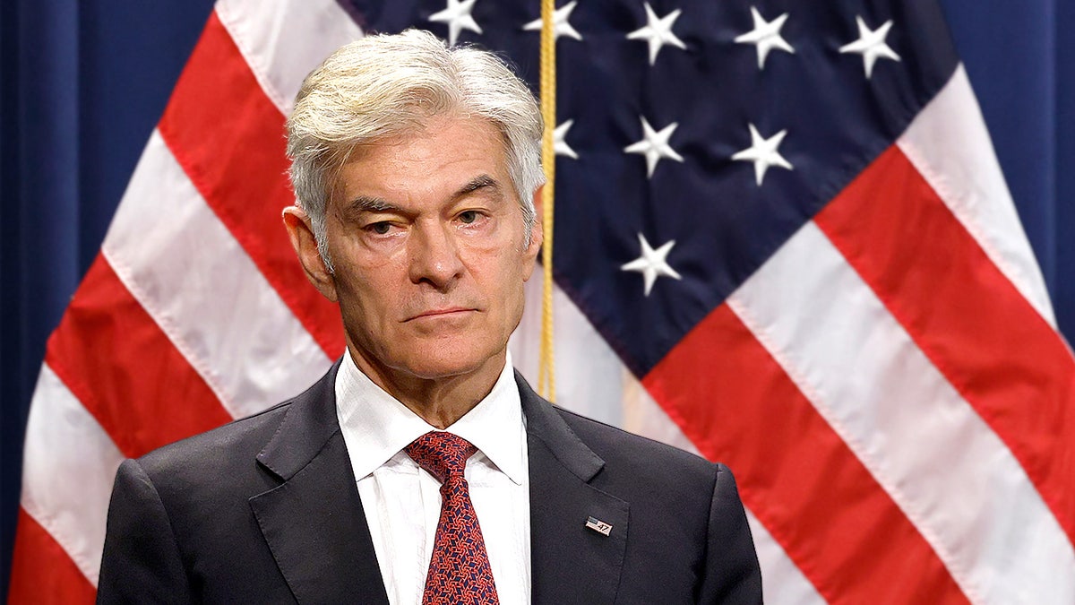 Mehmet Oz speaks at a Department of Justice press conference, behind him is an American flag.