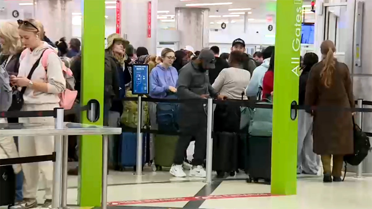 Travelers waiting in a long line at airport security checkpoint near