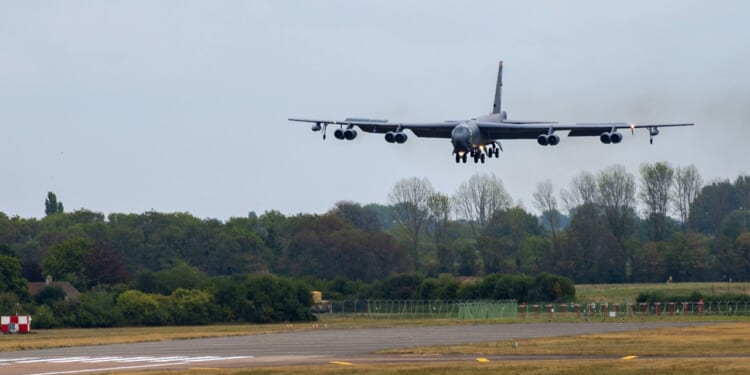 A B-52 Stratofortress descending to land on a runway.