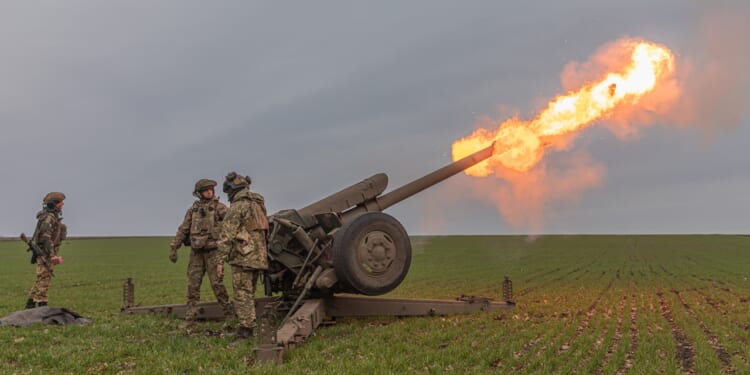 Three Ukrainian soldiers firing a cannon.