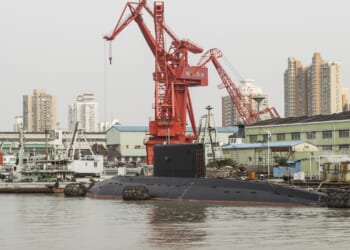 A Chinese submarine near a dock, underneath an enormous crane.