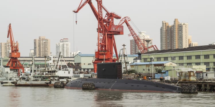 A Chinese submarine near a dock, underneath an enormous crane.