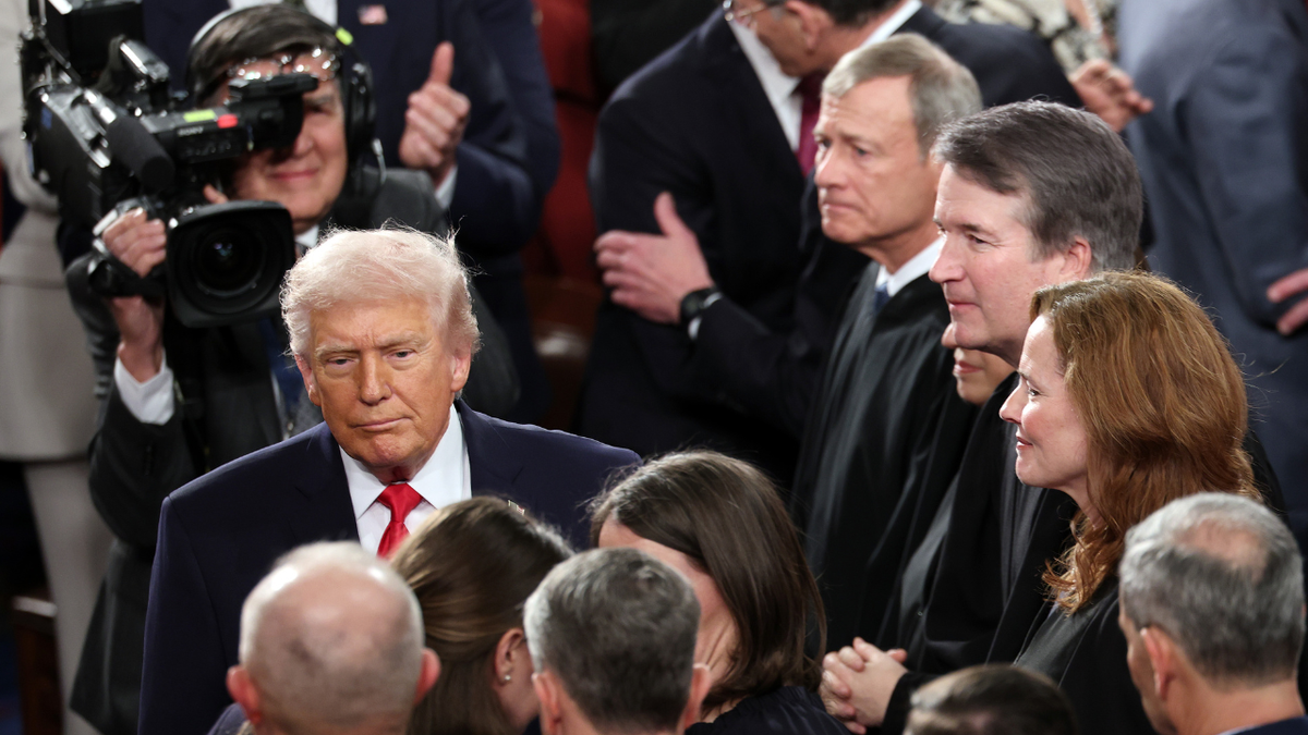 President Donald Trump walks past Supreme Court justices as he arrives for the State of the Union address.