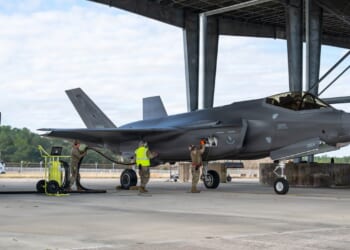 Soldiers on the ground fill an F-35 fighter jet's fuel tanks.