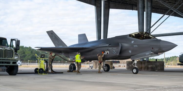 Soldiers on the ground fill an F-35 fighter jet's fuel tanks.