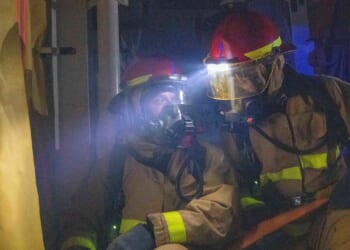 Two Navy firefighters using a hose.