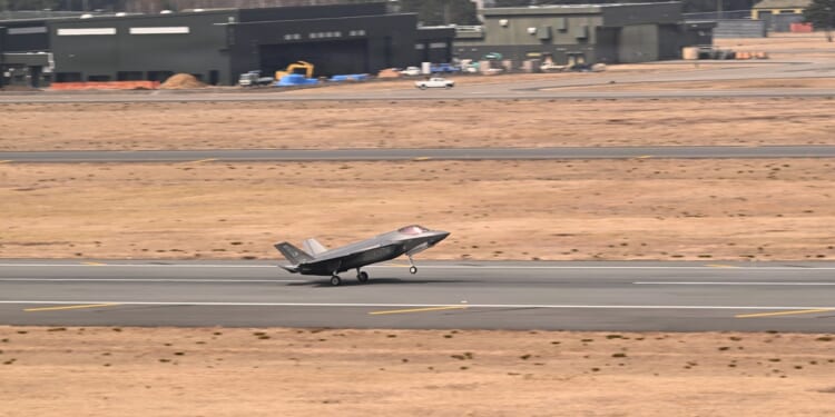 An F-35 landing on a runway next to two dry fields.
