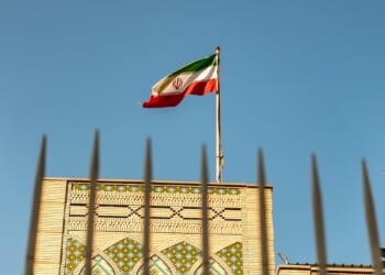 The Iranian embassy in Doha, Qatar, behind a high fence and with an Iranian flag flying overhead.