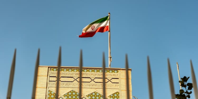 The Iranian embassy in Doha, Qatar, behind a high fence and with an Iranian flag flying overhead.