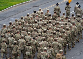 A group of US Army soldiers marching down a street during a military parade.