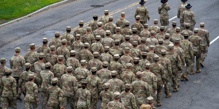 A group of US Army soldiers marching down a street during a military parade.