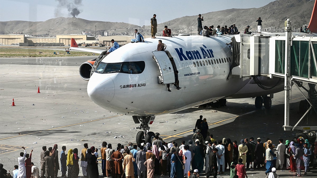 Afghan people climbing atop a plane at Kabul airport