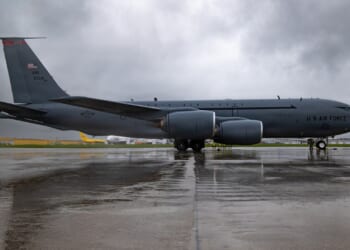 An Ohio Air National Guard KC-135 Stratotanker sits on a wet airport tarmac, underneath rain clouds.