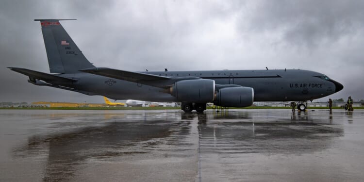An Ohio Air National Guard KC-135 Stratotanker sits on a wet airport tarmac, underneath rain clouds.