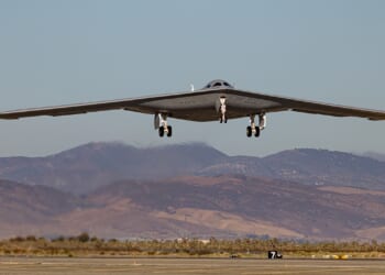 A B-21 Raider landing at an airfield.