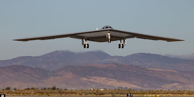 A B-21 Raider landing at an airfield.