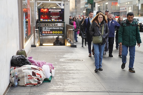 A homeless man sleeps on a street in New York City