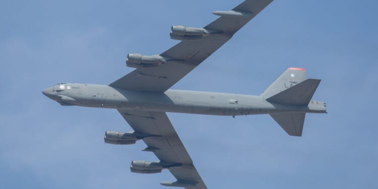 A B-52 Stratofortress in flight against a clear blue sky.
