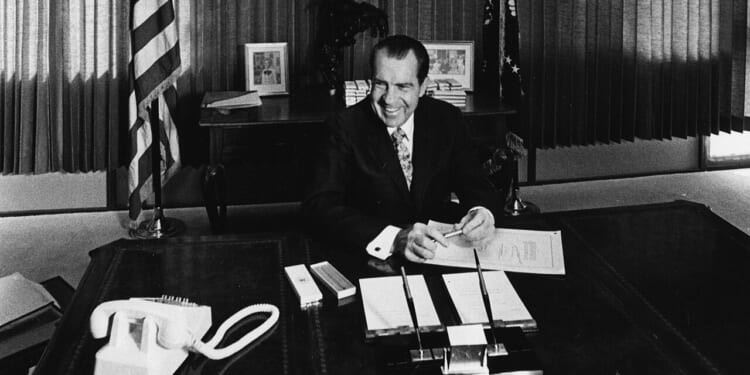 President Richard Nixon sitting at his desk.