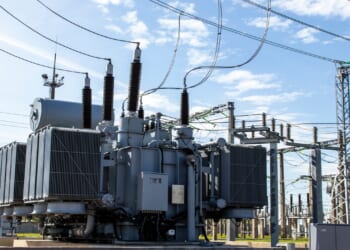 A high-voltage transformer surrounded by transmission lines and grid infrastructure.