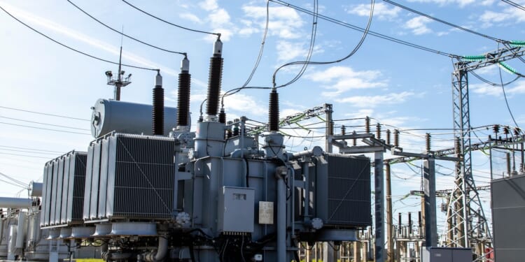 A high-voltage transformer surrounded by transmission lines and grid infrastructure.