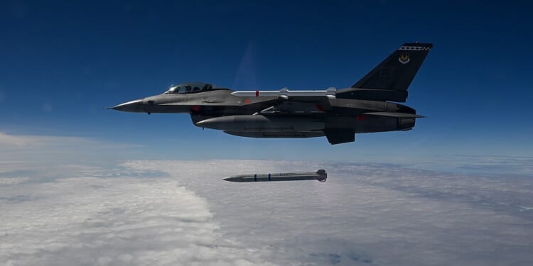 An F-16 Fighting Falcon fighter jet launching a Stand-in Attack Weapon over a cloudy sky.