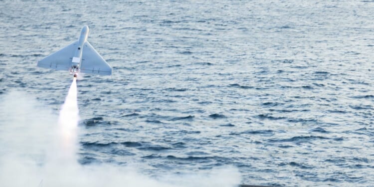 A LUCAS drone in flight, launched from an aircraft carrier deck.