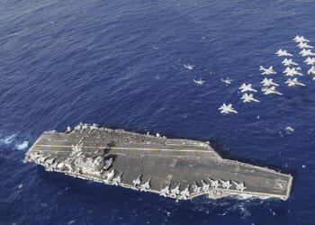 A group of US Navy aircraft fly over the USS Nimitz in 2013.