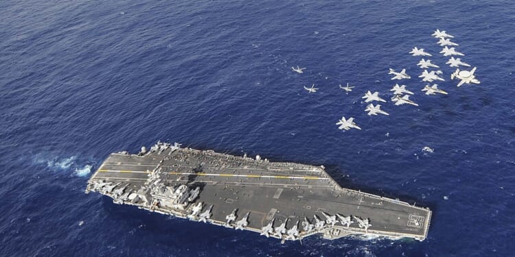 A group of US Navy aircraft fly over the USS Nimitz in 2013.