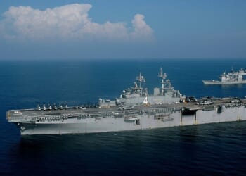 The USS Boxer, an amphibious assault ship, at sea on a sunny day.